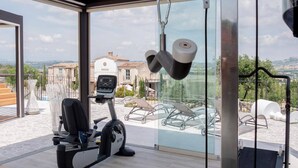 A home gym with exercise equipment, a view of a villa, and outdoor seating. - Villa Sant'Angelo (Alba Adriatica)