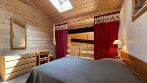 Una camera in una casetta di legno con un letto, una scrivania e una sedia.