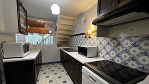 A compact kitchen with a microwave, toaster, and dishwasher. It features a tiled backsplash and a window with curtains. - BELMONT 26 – Village-center duplex close to the slopes (La Clusaz)
