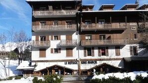 A multi-story building with balconies and a restaurant named "King Marcel" at the ground level. - GENTIANES 3 – Apartment in the village center and close to ski slopes – Wi-Fi (La Clusaz)