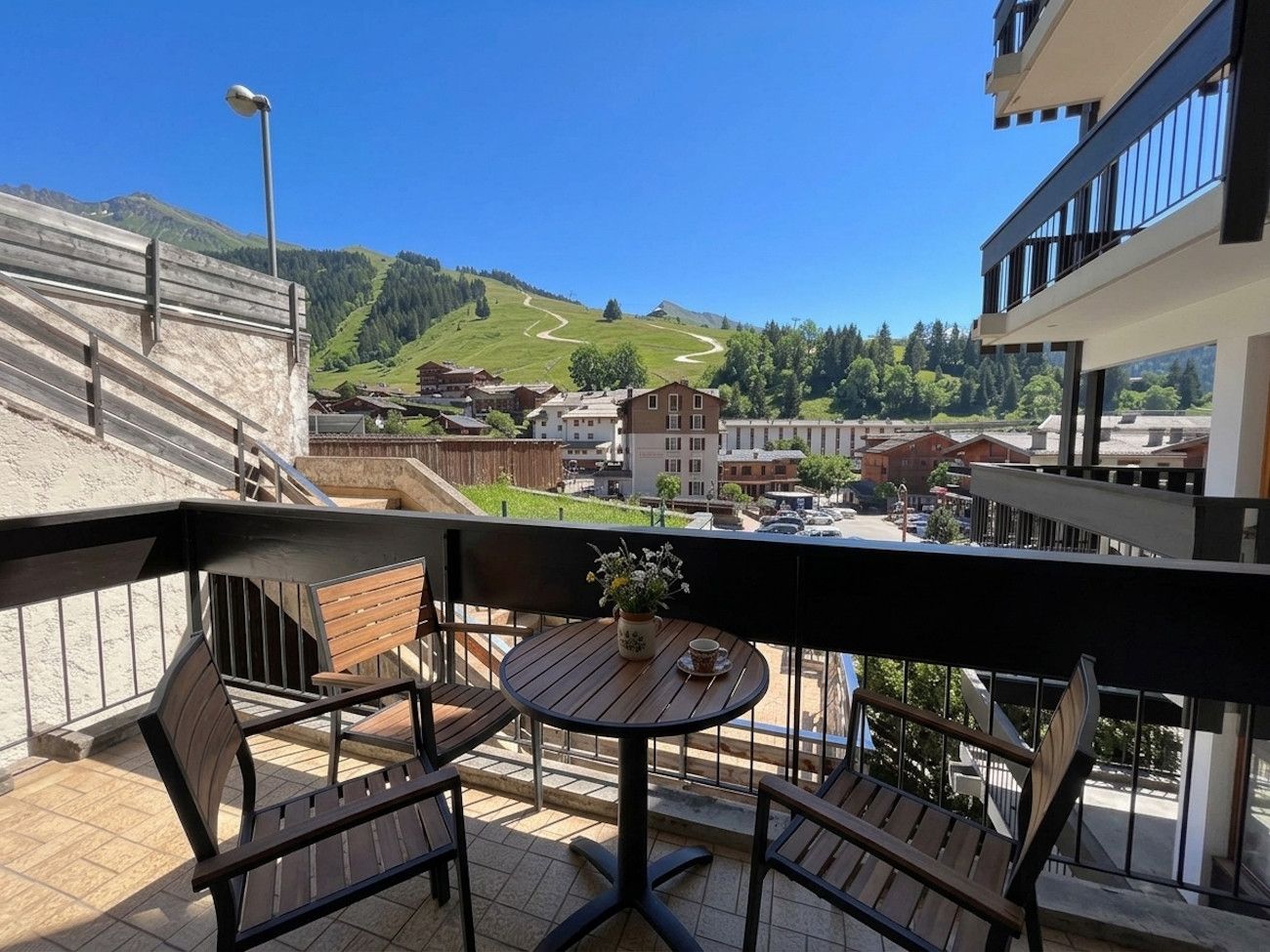 A balcony with a table and chairs, overlooking a mountainous landscape.