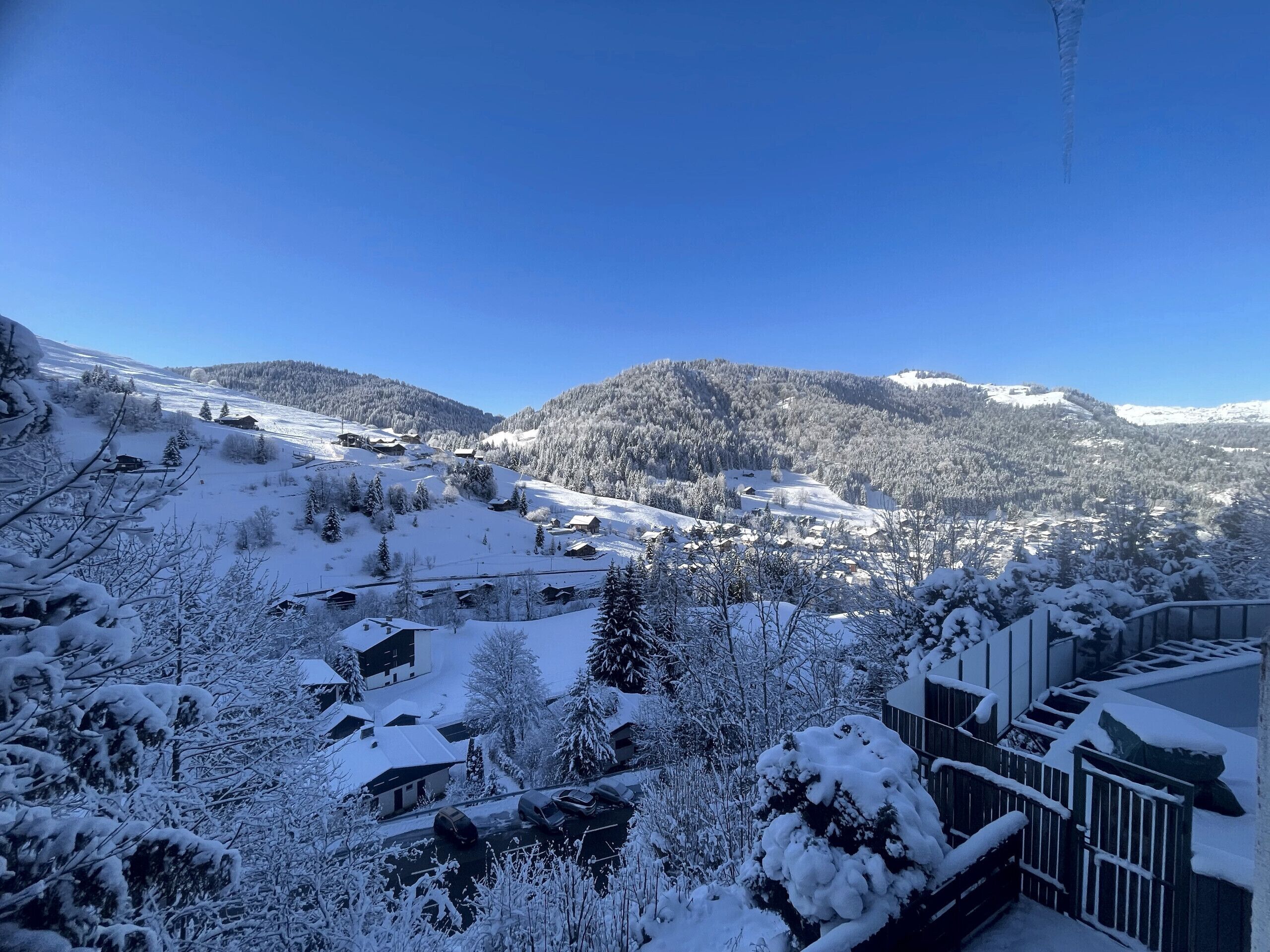 Paisaje nevado con casas y una montaña al fondo.