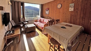 A cozy room with a wooden interior, a sofa, a dining table, and a TV.