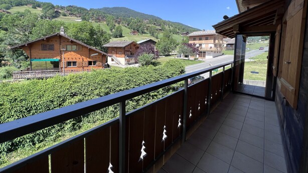 A balcony with a view of a rural landscape, including houses and a road. - PETIT LUTIN – Chalet on the slopes and in the village center – Garage and parking (La Clusaz)