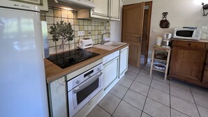 A compact kitchen with a refrigerator, stove, microwave, and toaster. - PETIT LUTIN – Chalet on the slopes and in the village center – Garage and parking (La Clusaz)