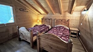 Ein Schlafzimmer einer Holzhütte mit zwei Betten, einem kleinen Tisch und einem Fenster.
