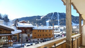 Un balcone in legno con vista su una città innevata e una montagna sullo sfondo.