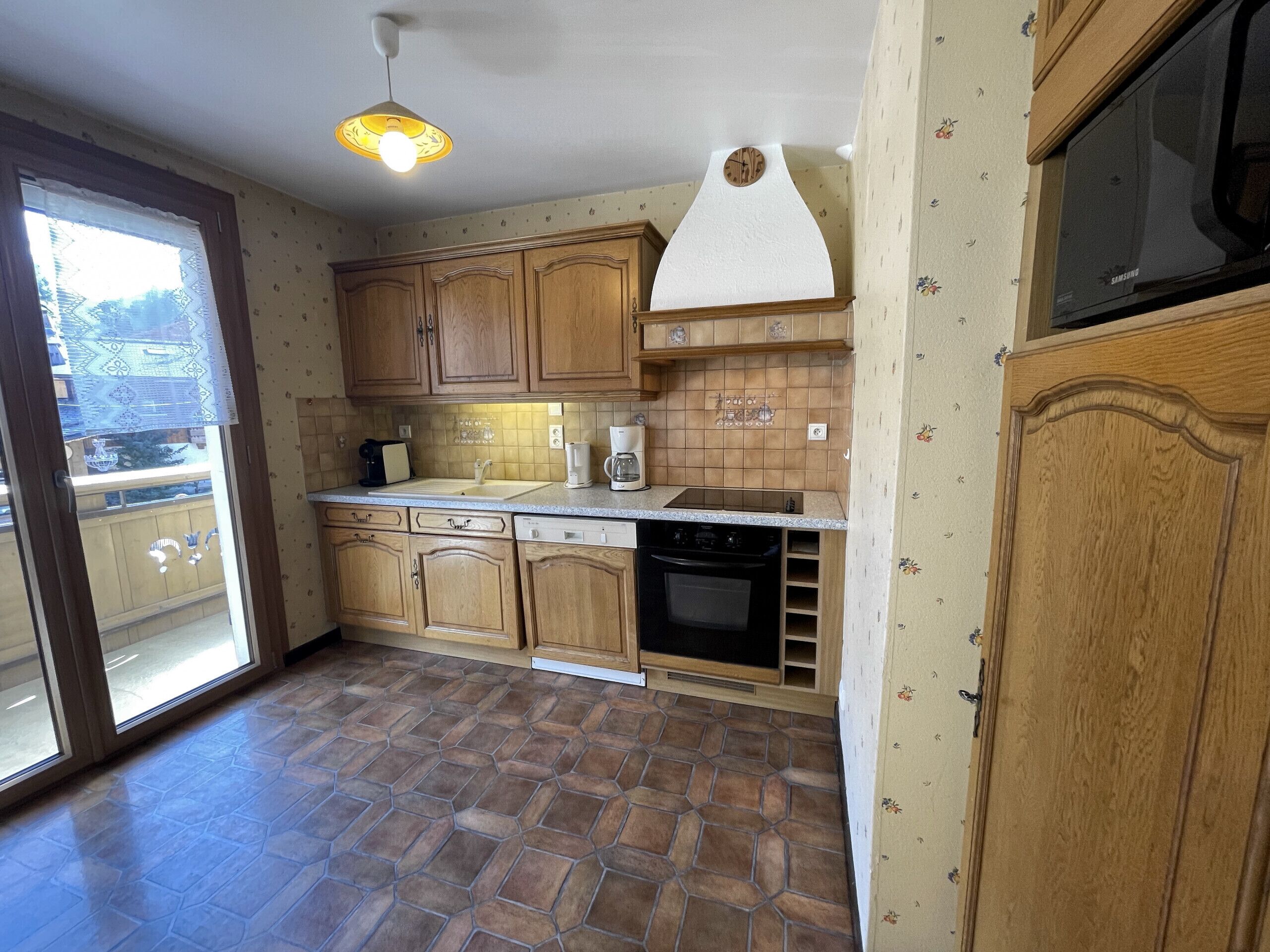 A kitchen with wooden cabinets, a built-in oven, and a microwave.
