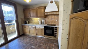 Una cucina con mobili in legno, forno a incasso e microonde.