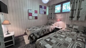 Ein Schlafzimmer mit zwei Betten, einem Fernseher, einer Lampe und einer Wand mit herzenmusterigen Vorhängen.