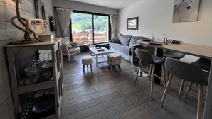 Ein modernes Wohnzimmer mit Essbereich, einer Couch, einem Couchtisch und Blick ins Freie.