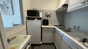 Eine kleine Küche mit Mikrowelle, Kühlschrank, Spüle und Geschirrgestell.