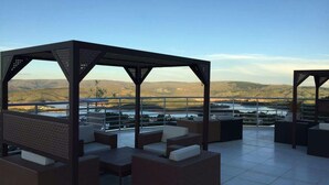 A rooftop terrace with outdoor seating, a pergola structure, and a scenic view of hills and water. - Casa no Mirante de Escarpas (Capitólio)