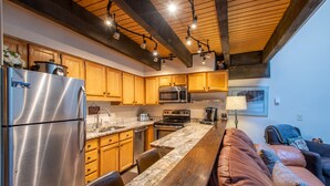 Une cuisine moderne avec des meubles en bois, des appareils électroménagers en acier inoxydable et un plan de travail en marbre.