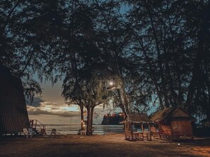 A beach scene with a thatched-roof hut, a wooden bench, and a swing set. - Blue Lagoon Home Trang (Kantang)