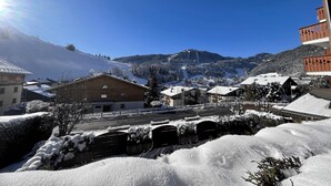 A snow-covered village with traditional wooden buildings, a clear sky, and a mountain in the background. - BIBLOS 15 - Apartment in the village center, close to the slopes - Parking (La Clusaz)