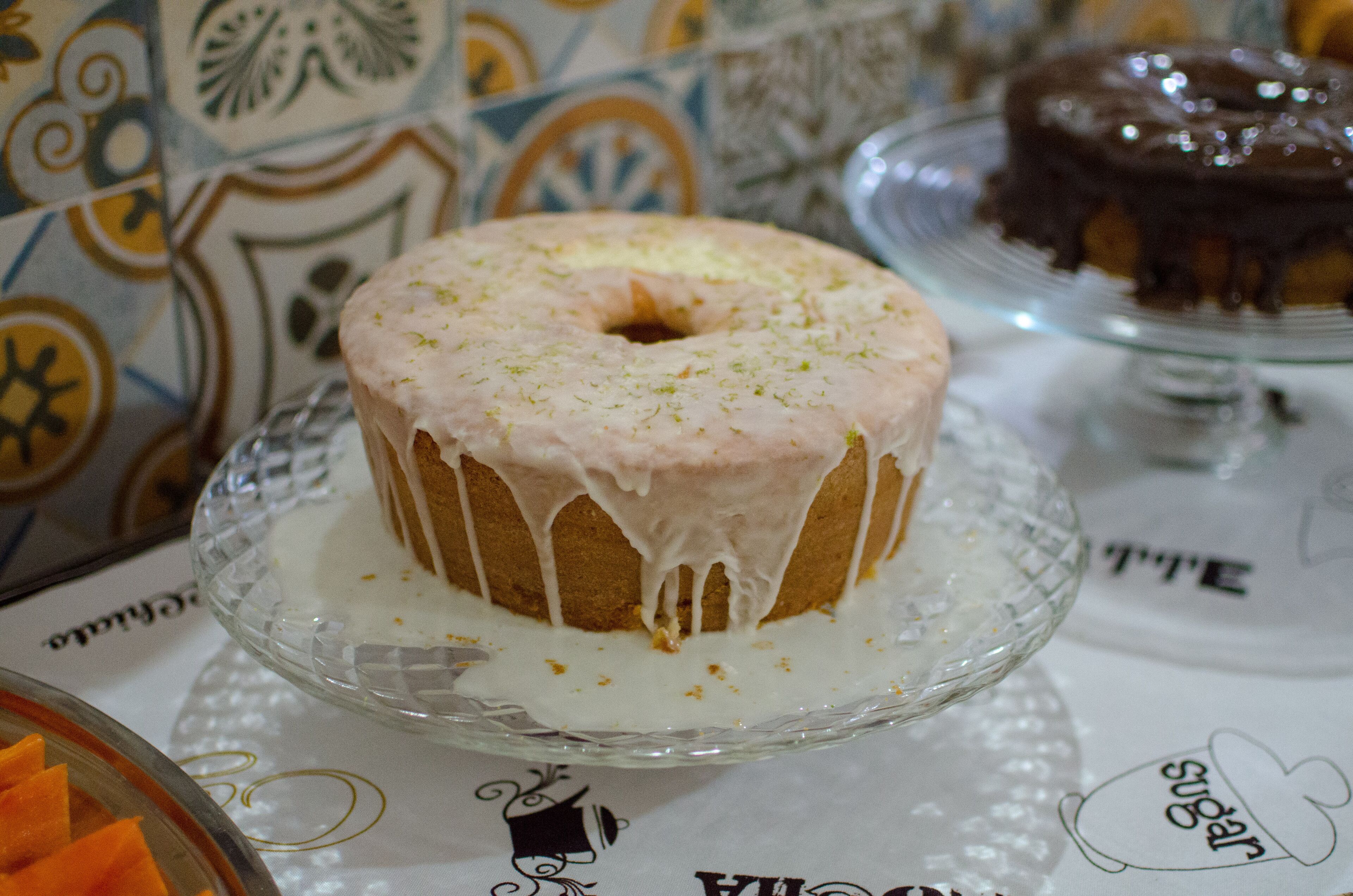 A cake with white icing on a glass plate.