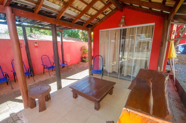 A covered patio area with wooden furniture, including a table and chairs, and a sliding glass door leading to an interior space. - Pousada Bonito Cama e Café (Bonito)