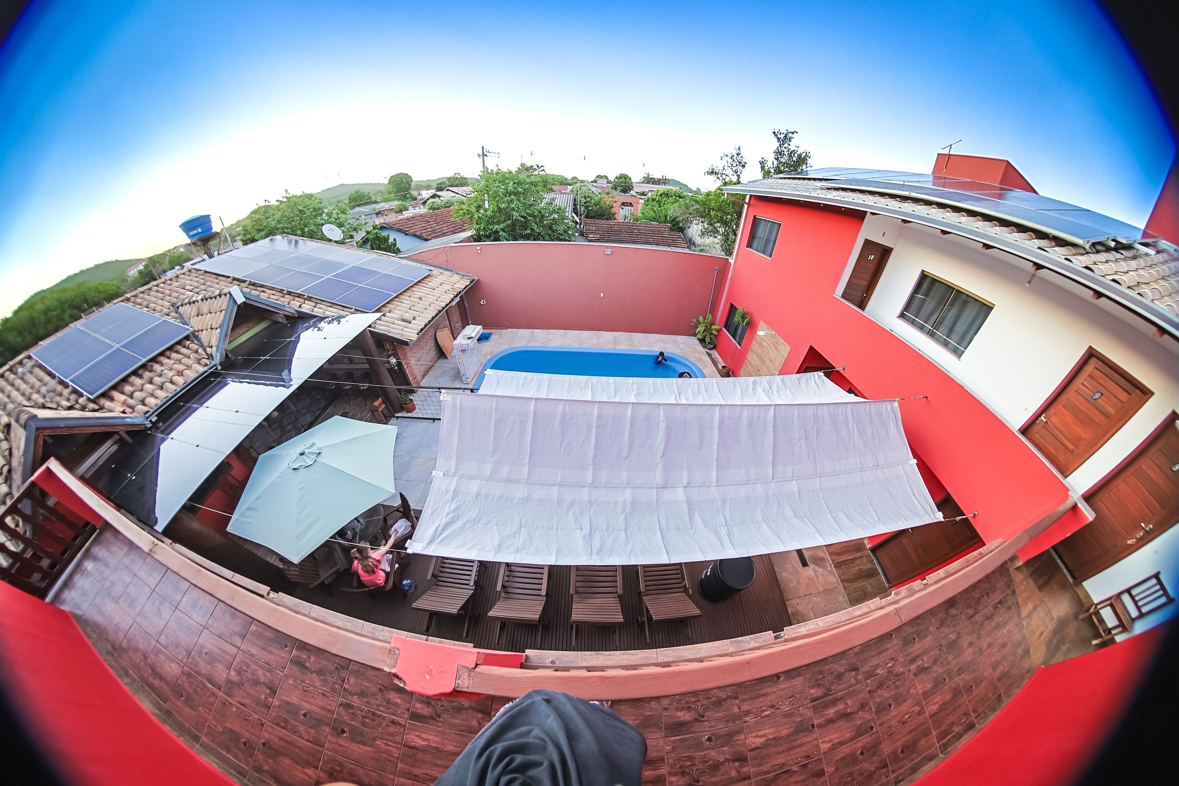 Una azotea con paneles solares, piscina y una zona de estar cubierta.