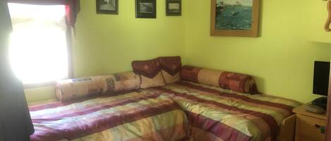 A bedroom with a bed, a dresser, and a wall with framed pictures.