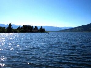 A calm lake with a house on the shore, surrounded by mountains.