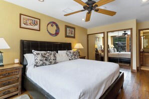 A spacious bedroom with a large bed, wooden headboard, and a ceiling fan. There are two bedside tables with lamps and a wooden nightstand. The room has a large mirror and artwork on the walls. - 3 BR/3BA Platinum Vail /Lionshead Penthouse
4 min walk to Lionshead gondola! (Vail)