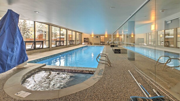 Una piscina interior con paredes de vidrio transparente, un jacuzzi y una zona cubierta.