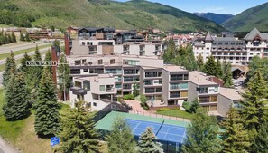 A modern hotel complex with multiple buildings, a tennis court, and surrounding greenery. - 3 BR/3BA Platinum Vail /Lionshead Penthouse
4 min walk to Lionshead gondola! (Vail)