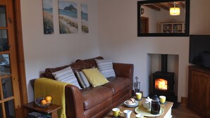 A cozy living room with a brown leather sofa, a coffee table with cups and a teapot, a fireplace, and a bookshelf. - 2 bedroom accommodation in Penmachno, near Betws-Y-Coed (Penmachno, near Betws-Y-Coed)
