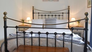 A bed with a metal frame, two bedside tables with lamps, a painting on the wall, and a window with curtains. - 2 bedroom accommodation in Penmachno, near Betws-Y-Coed (Penmachno, near Betws-Y-Coed)