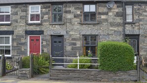 A stone building with a red door, a black door, and a window with a satellite dish. - 2 bedroom accommodation in Penmachno, near Betws-Y-Coed (Penmachno, near Betws-Y-Coed)