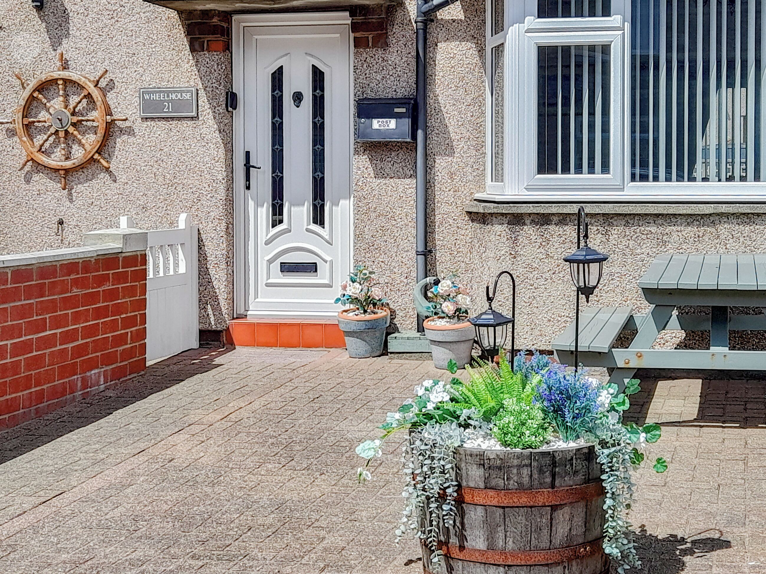 A house with a white door, a mailbox, a wheelhouse sign, and a mailbox with a post box label.