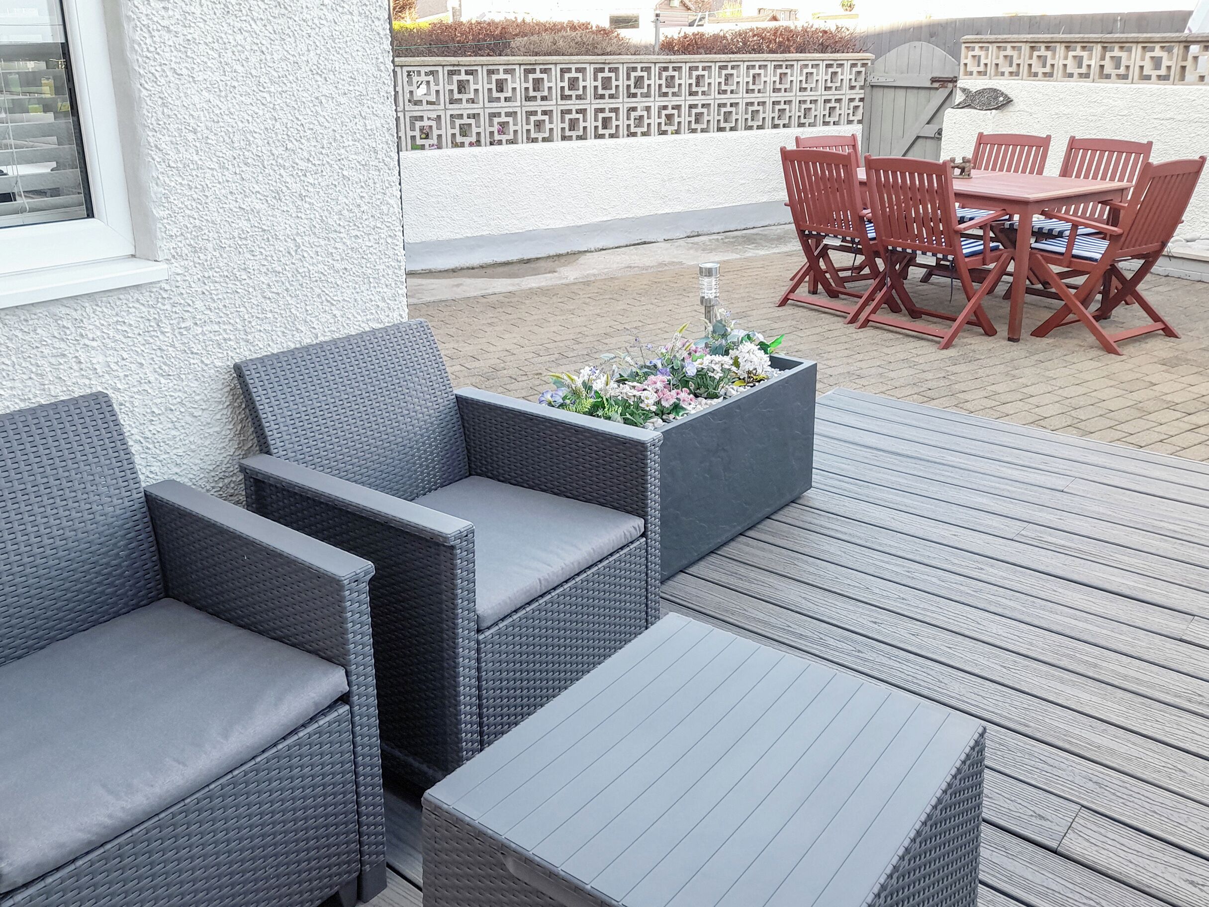 Een terras met rieten meubels, een tafel en stoelen.
