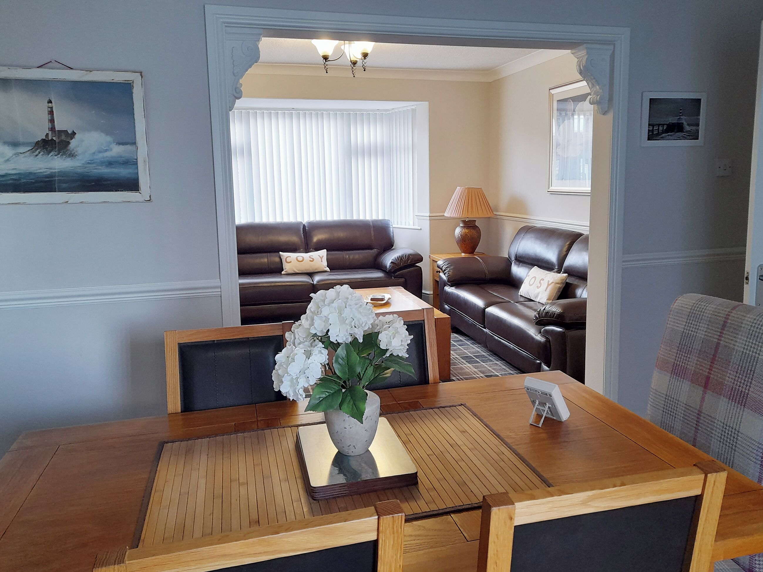 A living room with a wooden coffee table, a sofa, and a lamp.
