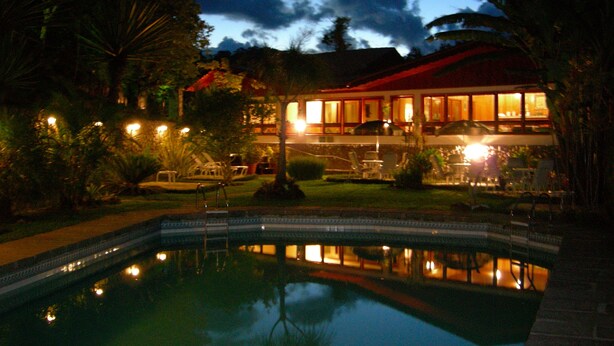 Un hotel con piscina, zona de estar al aire libre y un edificio con techo rojo.