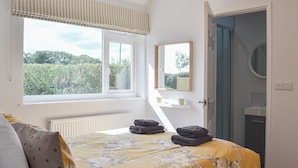 A bedroom with a bed, a window, a mirror, and a door. - 4 bedroom accommodation in Nomansland, near Tiverton (Nomansland, near Tiverton)