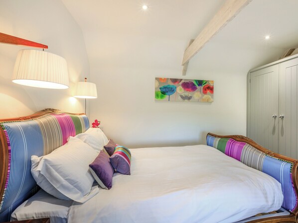 Un dormitorio con una cama grande, dos lámparas de noche, un cuadro de colores y un armario.