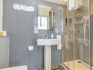 A modern bathroom with a glass shower enclosure, a white sink, and a mirror above it.