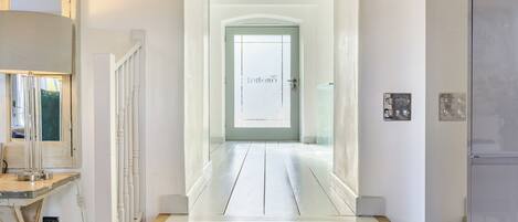 A hallway with a wooden staircase leading to a door with a frosted glass window.