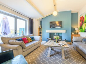 Un salon avec un canapé, une table basse et un téléviseur.