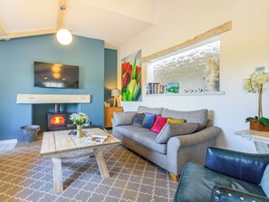 A cozy living room with a fireplace, a sofa, a coffee table, and a TV mounted on the wall. - 4 bedroom accommodation in Bishopswood, near Honiton (Bishopswood, near Honiton)