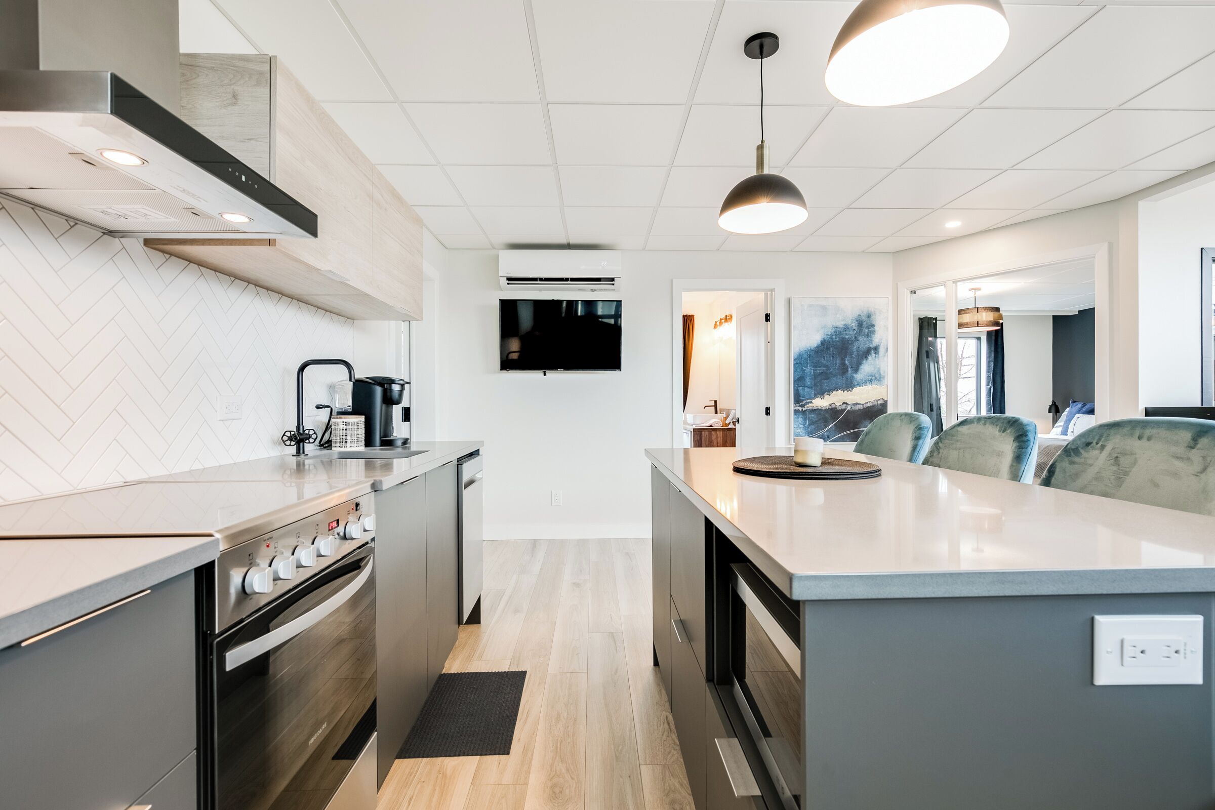 A modern kitchen with a central island, built-in oven, and a flat-screen TV.