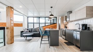 A modern kitchen with a central island, built-in appliances, and a large window providing natural light.