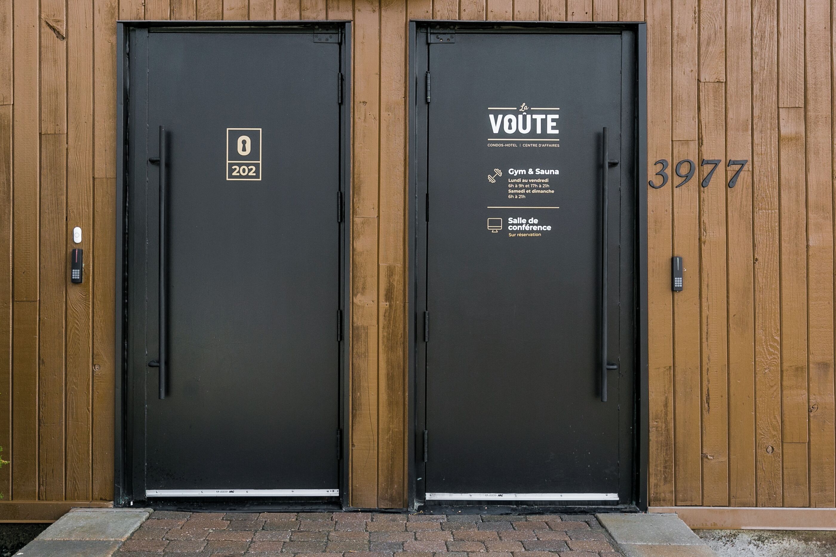 Due porte nere con pannelli di legno, una con il numero 202 e l'altra con il 3977.