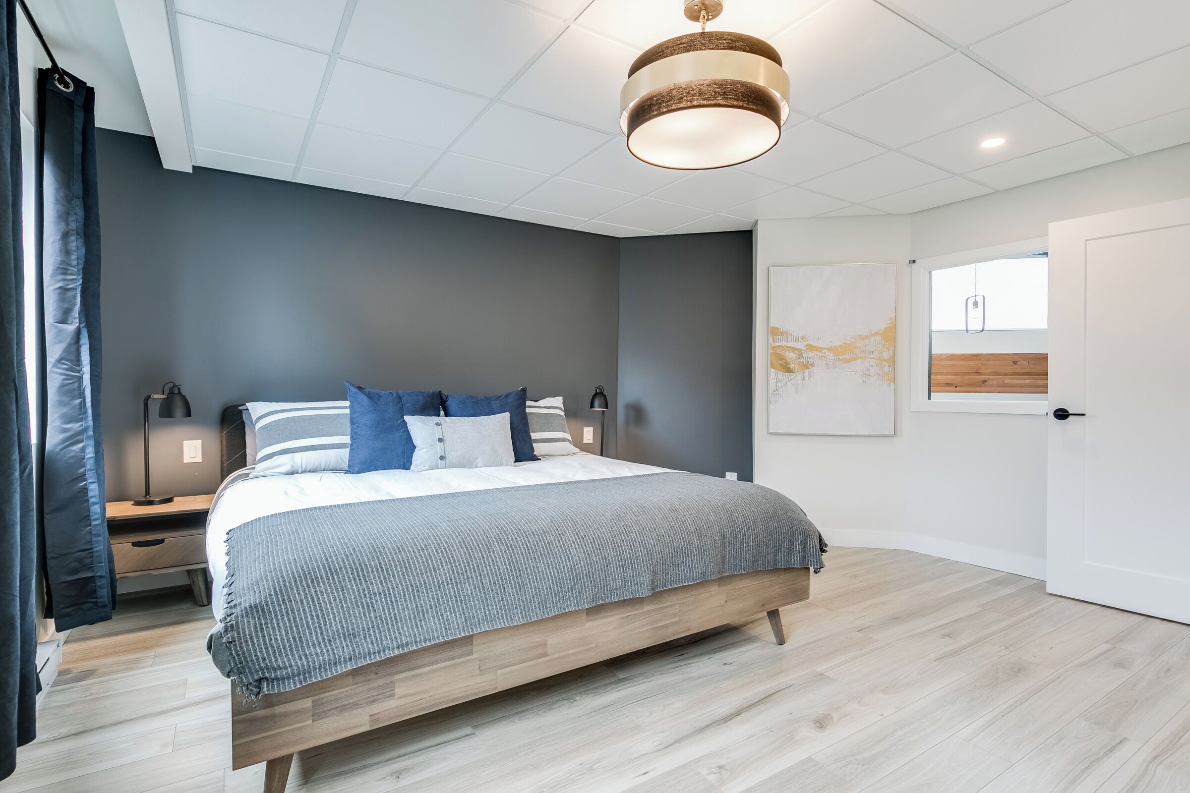 Ein modernes Schlafzimmer mit einem großen Bett, einem Holzkopfende und einer Deckenleuchte.