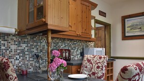 A dining area with a round table set for four, wooden cabinets, a tiled backsplash, and a painting on the wall. - 3 bedroom accommodation in Long Preston, near Settle (Long Preston, near Settle)