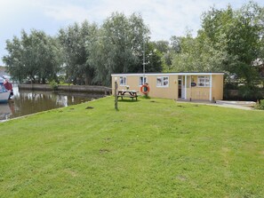 Ein kleines, eingeschossiges Gebäude mit Picknicktisch und Rettungsboje in der Nähe eines Gewässers.