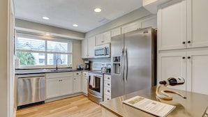 A modern kitchen with stainless steel appliances, white cabinetry, and a wooden countertop. - Beautiful Townhome 2 Blocks from the beach with beach cruisers! (Jacksonville Beach)