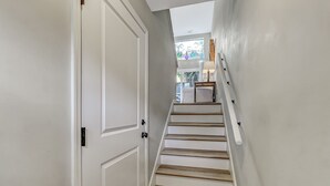 A staircase with white walls and wooden steps leading to a landing with a lamp and a window. - Beautiful Townhome 2 Blocks from the beach with beach cruisers! (Jacksonville Beach)