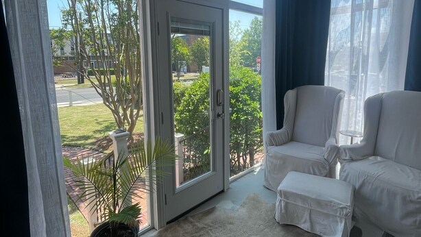 Una habitación con ventanas amplias, ventilador de techo y sofá blanco.